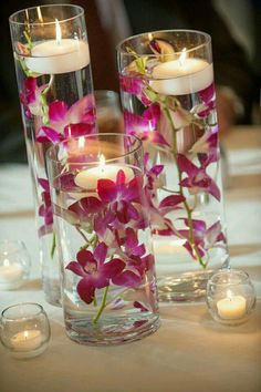 two vases with flowers and candles on a table