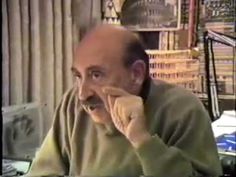 a man talking on a cell phone while sitting in front of a book shelf