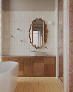 a bathroom with a sink, mirror and bathtub on the floor in front of a tiled wall