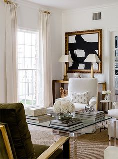 a living room filled with furniture and a painting on the wall above it's windows