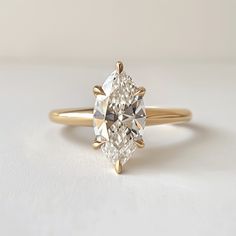 an engagement ring with a pear shaped diamond in the center, on a white surface