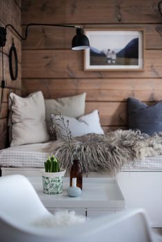 a living room with white furniture and wood paneling on the walls, along with two vases filled with flowers