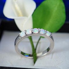 a ring with three opal stones sitting on top of a table next to a flower