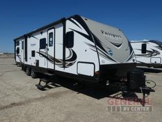 two white and black rvs parked in an empty lot