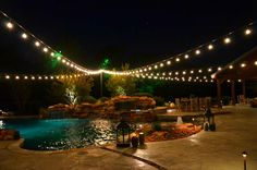 an outdoor pool with lights strung over it