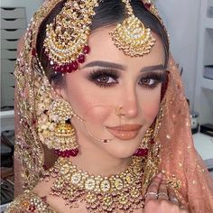 a woman in a bridal outfit with jewelry on her head and veil over her face