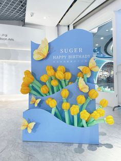 a blue sign with yellow flowers and butterflies on it