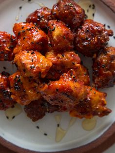 a white plate topped with chicken wings covered in sauce and seasoning on top of it