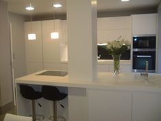 a white kitchen with two bar stools next to it