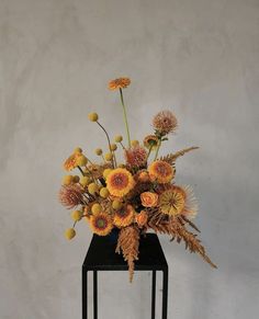 a vase filled with yellow flowers on top of a black stand