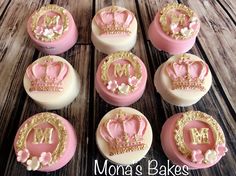 cupcakes decorated with pink and gold frosting are arranged on a wooden table