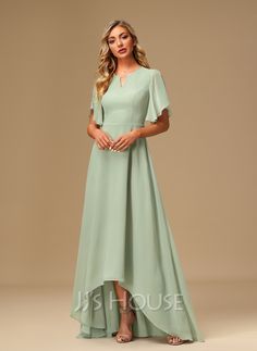 a woman wearing a long green dress with flutter sleeves and a high low hem skirt