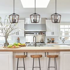 a kitchen island with three stools in front of it and an overhead light above the island