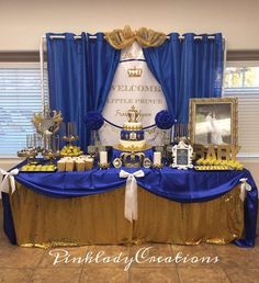 a table with blue and gold decorations in front of a curtained window at a party