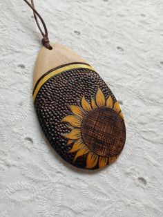 a wooden pendant with a sunflower painted on it