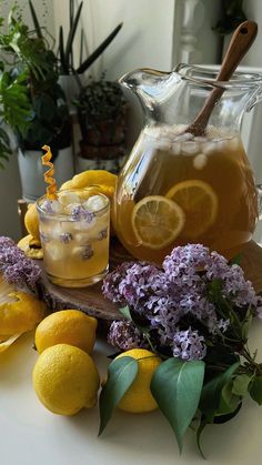 pitcher and glasses filled with lemonade sitting on a wooden table next to sliced lemons