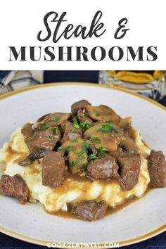 steak and mushrooms over mashed potatoes on a white plate