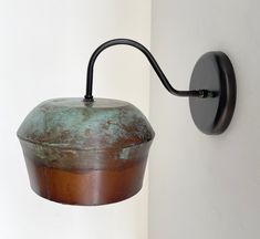 an old fashioned wall light hanging on the side of a white wall with rusted paint