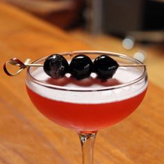 a cocktail with black olives on the rim