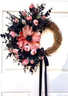 a wreath with pink and black flowers hanging on a door