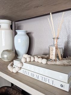 a shelf with books, vases and candles on it