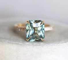 a ring with an aqua blue topazte surrounded by white and brown diamonds on a table