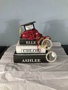 two books stacked on top of each other with graduation caps and rings attached to them