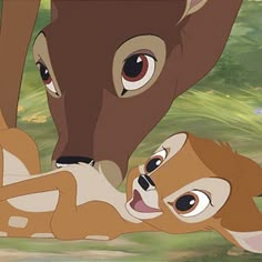 the young deer is laying down next to an older deer, who appears to be hugging it's face