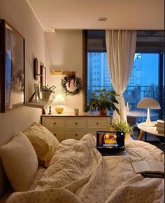 a laptop computer sitting on top of a bed next to a window in a bedroom