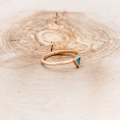 a gold ring with a blue triangle on it sitting on top of a piece of wood