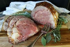 two pieces of meat sitting on top of a cutting board next to a knife and fork