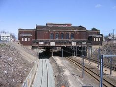 an old train station sitting on the tracks next to a dirt hill with no people