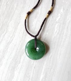 "Gorgeous green jade donut necklace. Jade pendant has a beautiful luster finish and is in a substantial size and weight. The jade is made from nephrite jade mined from British Columbia, Canada. Comes with a 24\" adjustablw hand knotted cord necklace with genuine jade beads. The pretty donut shape jade promotes good fortune and luck to the wearer. Green Jade is associated with the heart and root Chakras. Jade brings harmony and contentment to the wearer. In Asian cultures, Jade is revered as the Jade Gemstone Round Pendant Necklace, Jade Amulet Necklace With Round Pendant, Jade Round Pendant Necklace For Healing, Round Jade Spiritual Necklaces, Round Jade Necklace For Spiritual Style, Spiritual Round Jade Necklaces, Spiritual Round Jade Necklace, Spiritual Jade Round Pendant Necklace, Handmade Jade Necklaces For Good Luck