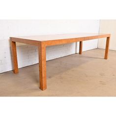 a wooden table sitting on top of a cement floor next to a white brick wall