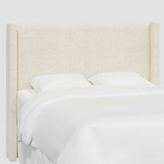 an upholstered headboard with white sheets and pillows