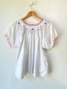 Vintage Mexican Novelty Imports Embroidered Top! So precious! 100% cotton in white with colorful flowers embroidered along the collar and on the pockets. Would best fit M/L though it has XL handwritten on the tag, please refer to measurements. In overall good condition with some signs of wear throughout. Approx. Measurements: Underarm to Underarm: 19" Sleeve Length: 5.5" Length: 26" Electric Feathers, Ryan Roche, Flowers Embroidered, Christian Wijnants, Ace And Jig, Raquel Allegra, Magnolia Pearl, Vintage Mexican, Embroidered Top