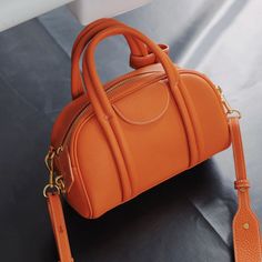 Master the understated aesthetic with our bowling bag in orange. The elegant neutral finish will put you in a calm mood and have a soothing effect during a hectic work week. Versatile enough to go with everything in your wardrobe, it will take the work out of dressing up. You can carry it by the top handles or clip on the detachable shoulder strap to keep your hands free. Create a chic monochromatic outfit by pairing the bag with taupe pants and a crisp white blouse.Weight: 360 gWidth (cm): 10 c Luxury Yellow Satchel With Detachable Handle, Orange Bag Aesthetic, Orange Bags, Bowling Bag, Mini Bowling, Orange Handbag, Modern Handbag, Mini Moderns, Monochromatic Outfit