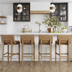 a kitchen with white walls and wooden floors, three bar stools in front of the counter