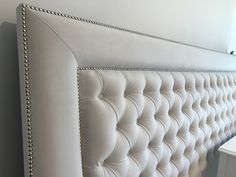 an upholstered white headboard with beading and nail polishing on it