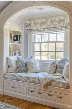 a window seat with pillows on it in front of a book shelf and bookshelf