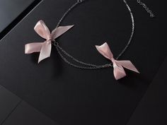 Rannka's dusty pink bow necklace with ribbons is a thoughtful romantic birthday gift and anniversary jewelry for a girlfriend. The silver jewelry piece is ideal for youth, and a charming summer elegant chain necklace.  𝐒𝐈𝐙𝐄: ➤ Adjustable Fits Circumference from 16″ - 20″ (40.6cm - 50.8cm)  𝐃𝐄𝐓𝐀𝐈𝐋𝐒: ➤ Materials: Stainless Steel, Ribbon ➤ Ready to Ship -The Rannka Bow Necklace features two dusty pink ribbon bows and a double stainless steel chain design. -Great for a fun summer day and night.  𝐒𝐔𝐆𝐆𝐄𝐒𝐓𝐄𝐃 𝐂𝐀𝐑𝐄: Use water and a drop of mild detergent. Rinse, then line dry. Always make sure to wipe off water and dry your jewelry completely after cleaning. Do not use any products containing alcohol. Be sure to take off your jewelry before swimming, showering, etc.  𝐂𝐎𝐎? Pink Ribbon Jewelry As Gift, Pink Ribbon Jewelry For Gifts, Pink Ribbon Jewelry Gift, Dainty Ribbon Jewelry For Gifts, Pink Bow Necklace For Party, Pink Party Jewelry With Butterfly Knot Detail, Pink Party Jewelry With Butterfly Knot, Feminine Ribbon Jewelry For Party, Gift Jewelry With Pink Bow