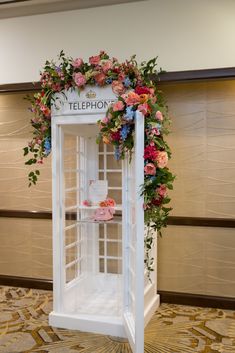 a phone booth decorated with flowers and greenery