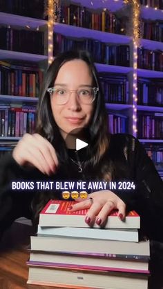 a woman sitting in front of a stack of books