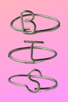 three metal rings with the letters b and c in them on a pink background,