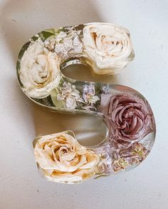 the letter s is made out of flowers and glass vases on a white surface