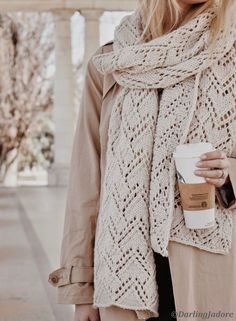 a woman holding a coffee cup and wearing a scarf