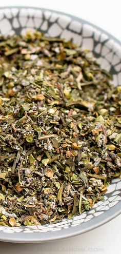 a white bowl filled with dried herbs on top of a table