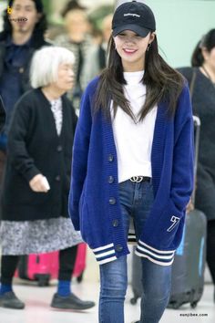 a young woman is walking through an airport with her hat on and luggage behind her