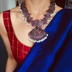 a woman in a red and blue sari with a necklace on her neck,