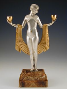 a statue of a woman holding two candles in her hands and standing on a marble base